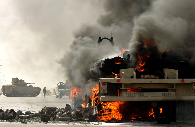 American soldiers took positions around a burning supply truck after their convoy was attacked by a small explosive device, a highway west of Baghdad, October 2, 2004.